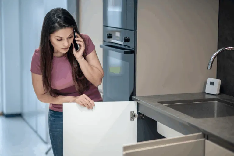 Woman standing in a kitchen, checking the drawer under the sink
