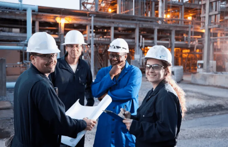 Engineers smiling and standing in front of manufacturing plant
